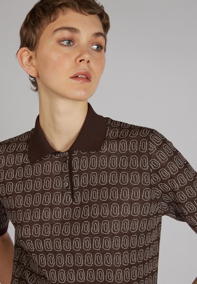 Camisa polo marrón con un patrón geométrico, mangas cortas y un cuello oscuro. Tres botones en el cuello y un acabado texturizado.