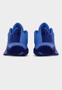 Ζευγάρι μπλε αθλητικά παπούτσια που φαίνονται από πίσω, με υφή σκούρου μπλε σόλας και έλξεις στους φτέρνες.