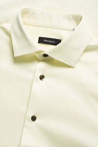 Lichtgeel overhemd met een getextureerd visgraatpatroon, korte kraag, bruine knopen en een zwart label met de tekst "Matinique."