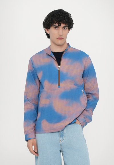 Blue and pink tie-dye pullover. Features a half-zip collar, ribbed texture, and zippered side pockets. Soft, lightweight fabric.