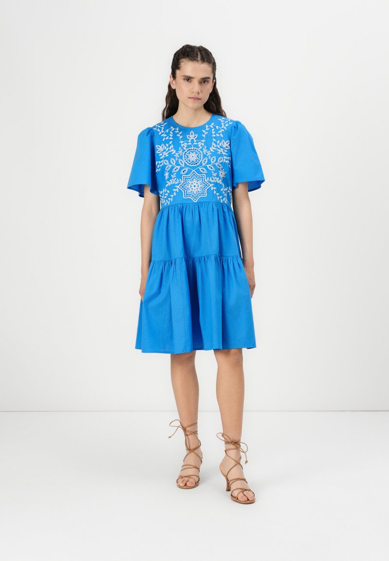 Blue dress featuring an embroidered bodice, short flutter sleeves, and a tiered skirt. Material appears smooth with a matte finish.