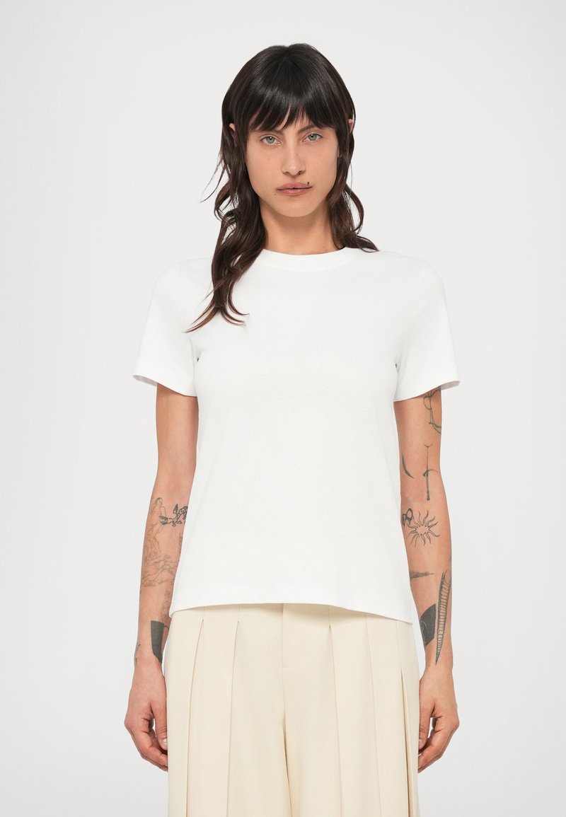 Biele bavlnené tričko s okrúhlym výstrihom, krátkymi rukávmi a voľným strihom. Jednoduchý dizajn bez viditeľných vzorov alebo akcentov.