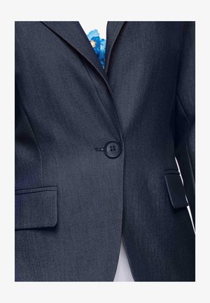 Veste blazer bleu marine foncé à un bouton avec revers crantés et poches à rabat, portée sur une chemise blanche avec un détail floral bleu.