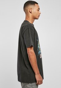 Black cotton t-shirt with short sleeves and a loose fit. Features colorful graphic design on the front. Soft texture, casual style.