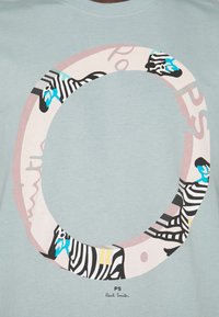 Hellblaues T-Shirt mit einem runden, bunten Zebra-Design in Pink- und Schwarztönen. Enthält den Text "PS" und "Paul Smith" am unteren Rand.