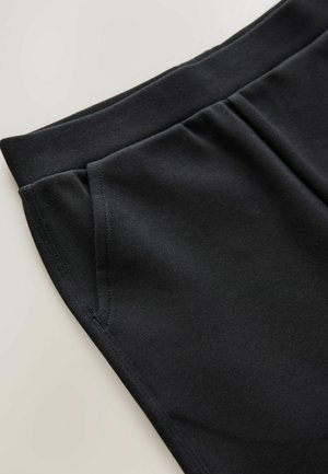 Pantalones con cintura elástica negra que cuentan con dos bolsillos laterales, textura suave y un diseño simple y ajustado.