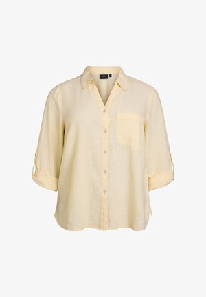 Kolliga kollane linane särk, nupukinnitusega ning rinnataskuga. Omab ülespoole keeratavaid varrukaid ja lõdva lõikega. Tekstuuriga kangas.