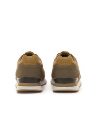 Un par de zapatillas marrones y beiges vistas desde atrás, con una suela blanca y la marca "mtng" en la zona del talón.