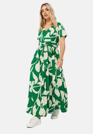 Grøn og hvid blomstrede maxi kjole med omslagsdesign, korte ærmer, bindebælte og tekstureret stof, parret med hvide sneakers.