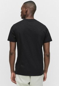 Sort kortærmet t-shirt med rund hals, lavet af struktureret katoen, med en afslappet pasform og et enkelt design uden synlige logoer.