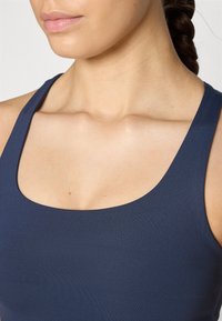Marineblå atletisk tank topp med firkantet utringning, laget av et glatt materiale, med brede skulderstropper og en tettsittende design.