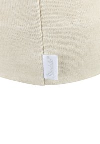 Cream-colored cotton cap with ribbed texture. Features a small white fabric label with the brand name stitched on the side.