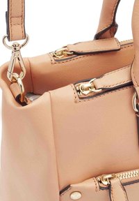 Lichtroze leren handtas met gouden accenten, voorzien van ritsen, een afneembare schouderband en contrasterende stiksels langs de randen.