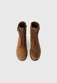 Une paire de bottines en daim marron à lacets avec des zips latéraux, vue d'au-dessus sur un fond blanc uni.