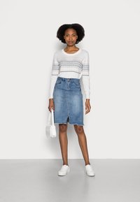White long-sleeve sweater with geometric pattern, paired with a blue denim pencil skirt. White sneakers and a small white handbag.
