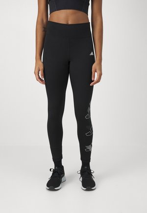 Black athletic leggings with a high waist, smooth texture, and reflective silver logo accents along one side. Suitable for workouts.