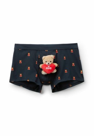 Granatowe bokserki z małymi nadrukami misiów oraz pluszowy miś trzymający czerwone serce z napisem "BĄDŹ MÓJ" przymocowany z przodu.