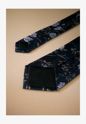 Blumenbindem mit einem dunklen marineblauen Seidenstoff, der goldene und silberne Blumenmuster aufweist; spitz zulaufende Enden mit einem glatten schwarzen Futter.