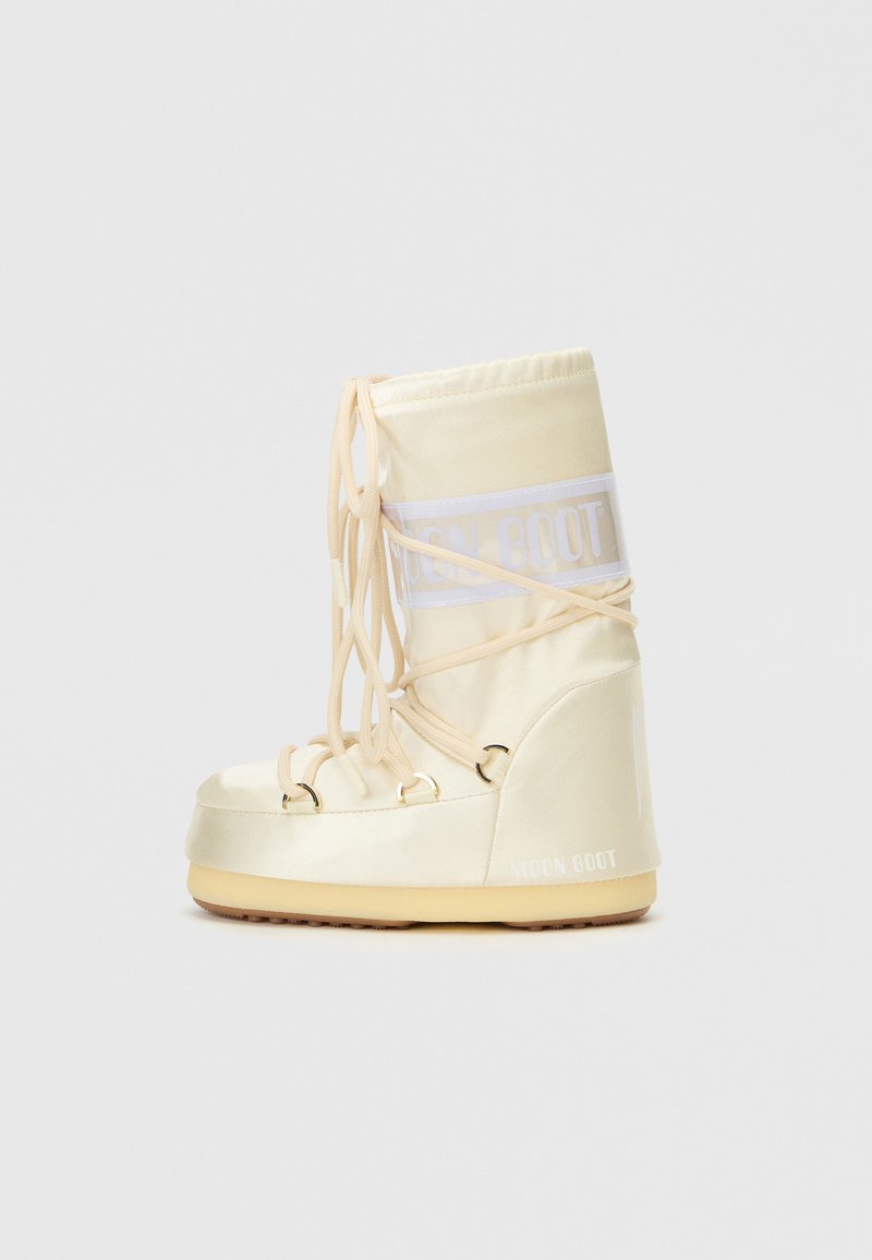 Beige Moon Boot mit satinierter Oberfläche, ausgestattet mit einer Schnürung an der Vorderseite, Logo-Akzent und Gummisohle; zeigt eine runde Zehenpartie und einen gepolsterten Schaft.