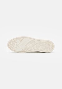 Suola della scarpa con un motivo mappato testurizzato, di colore beige. Il design include il logo del marchio e dettagli intricati in linea.