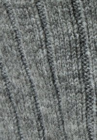 Tejido gris de punto con un patrón texturizado que presenta líneas diagonales elevadas y superpuestas, y un acabado suave y difuso.