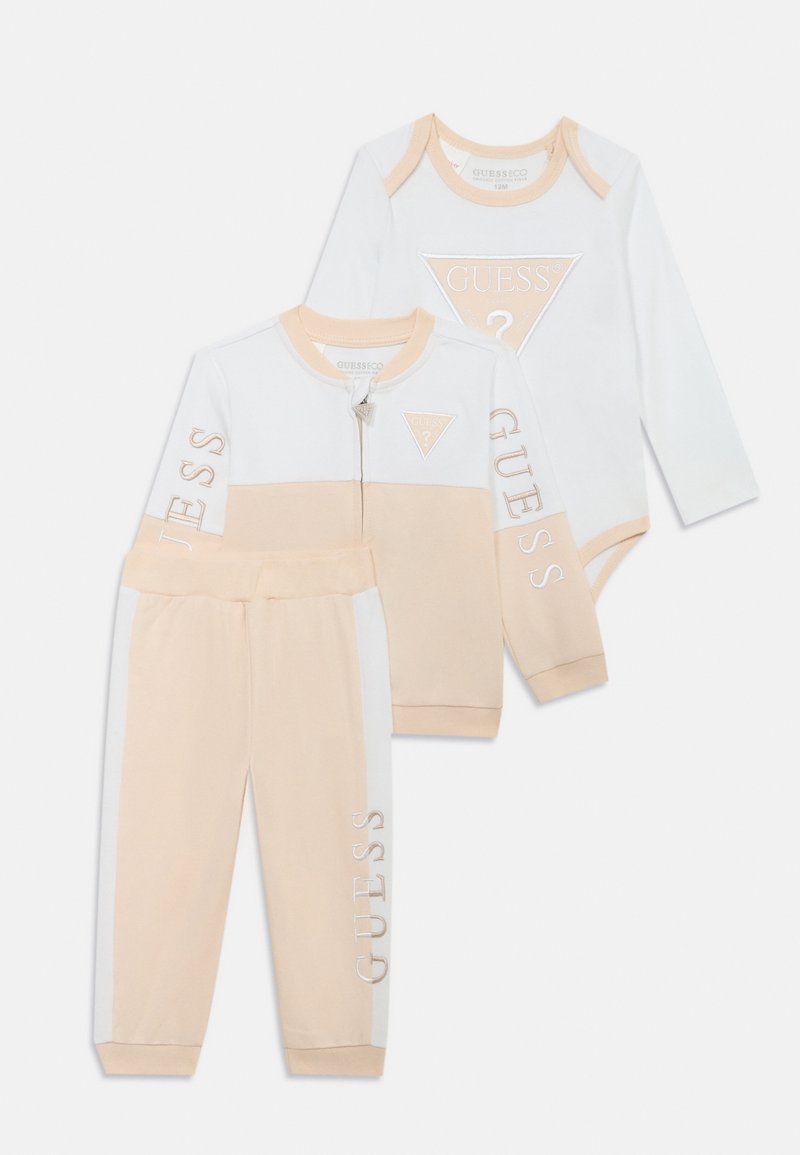 Tryse dalių komplektas mažiesiems, kuriame yra užtrauktuku užsegama striukė, ilgomis rankovėmis bodysuitas ir kelnės, švelniame smėlio ir baltame atspalvyje, su logotipo akcentais.
