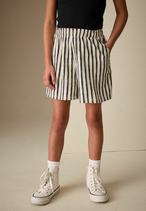 Triibulised lühikesed püksid kreemjas ja mereväes, millel on elastne vöökoht ja küljetaskud. Kandmiseks valgete kõrgete tenniste ja ülespööratud sokkidega.