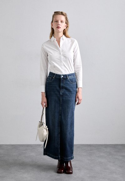 Tummansininen denim-maksihame etutaskuilla, yhdistetty valkoiseen napitettuun paitaan ja ruskeisiin nahkasaapikkaisiin. Pieni valkoinen laukku mukana.