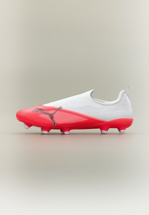 Λευκό και κόκκινο ποδοσφαιρικό παπούτσι Puma με κομψό, χωρίς κορδόνια σχεδιασμό και αγκίστρια στη σόλα για χρήση σε σκληρό έδαφος.