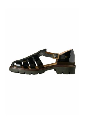 Sandale en cuir verni noir avec talon fermé, plusieurs brides sur le pied, fermeture à boucle et semelle basse et robuste.