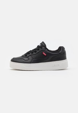 Baskets en cuir noir avec une semelle blanche, présentant un design à lacets, des accents perforés et un petit logo rouge Levi's sur le côté.