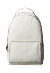 Bílý látkový batoh s zaobleným vrškem, přední kapsou na zip, vystouplým logem a texturovaným povrchem. Obsahuje rukojeť pro přenášení.