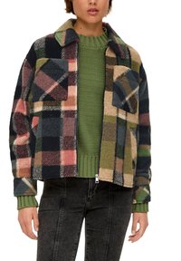 Kratkowana polarowa kurtka w odcieniach niebieskim, zielonym, różowym i beżowym; posiada dwie kieszenie na piersi oraz zamek z przodu. Nosi się ją na zielonym swetrze dzianinowym.