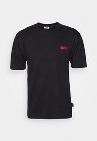 Černé tričko s krátkým rukávem vyrobené z bavlny s kulatým výstřihem; na levé části hrudi se nachází červené logo GCDS. Jednoduchý a solidní design.