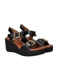 Zwarte wedge sandalen met gevlochten platformzolen, verstelbare gouden gespen en bruin gevoerde voetbedden.