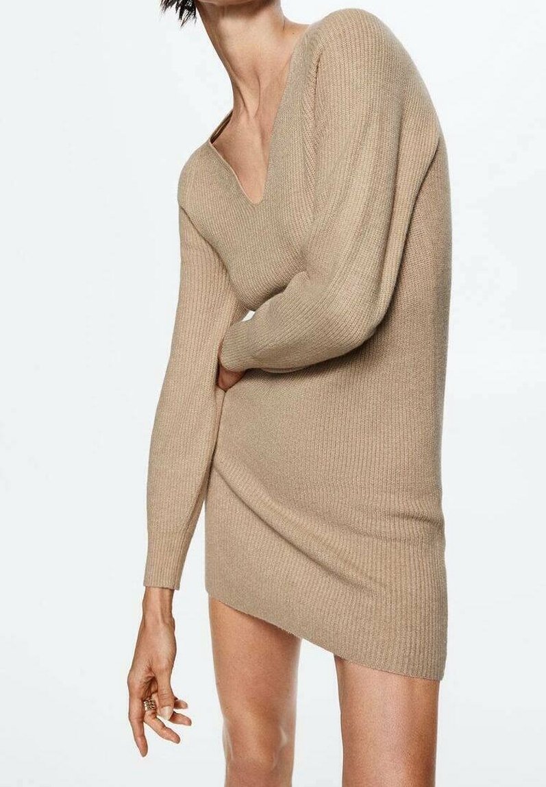 Robe en maille côtelée beige avec un décolleté en V profond, des manches longues et une silhouette ajustée. Texture douce et détail d'ourlet légèrement asymétrique.