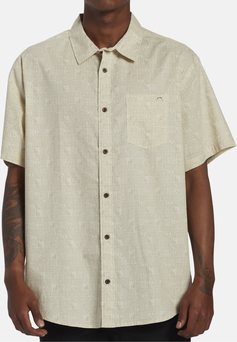 Korte mouw beige overhemd met een subtiel geometrisch patroon, zak op de linkerborst en bruine knopen.