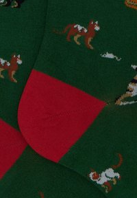 Calzini verdi con motivi di cani colorati, con un accento rosso nella zona delle dita. Il materiale sembra morbido e lavorato a maglia, con dettagli di cucitura visibili.