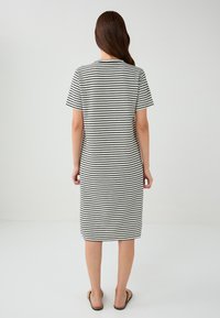 Robe rayée noire et blanche à manches courtes, longueur genoux, coupe décontractée, fabriquée en tissu doux, avec un col rond simple.