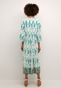 Rochie albă cu imprimeu floral verde, mâneci three-quarter, strângere în talie, tiv în straturi și margine decorativă teal în partea de jos.
