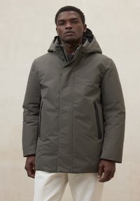 Parka imbottito verde con cappuccio, cerniera frontale e due tasche laterali con cerniere nere. Texture liscia e design minimalista.