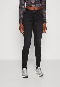 Svarta smala jeans i denim med en slät textur. Har en klassisk design med 5 fickor och en knappstängning fram.