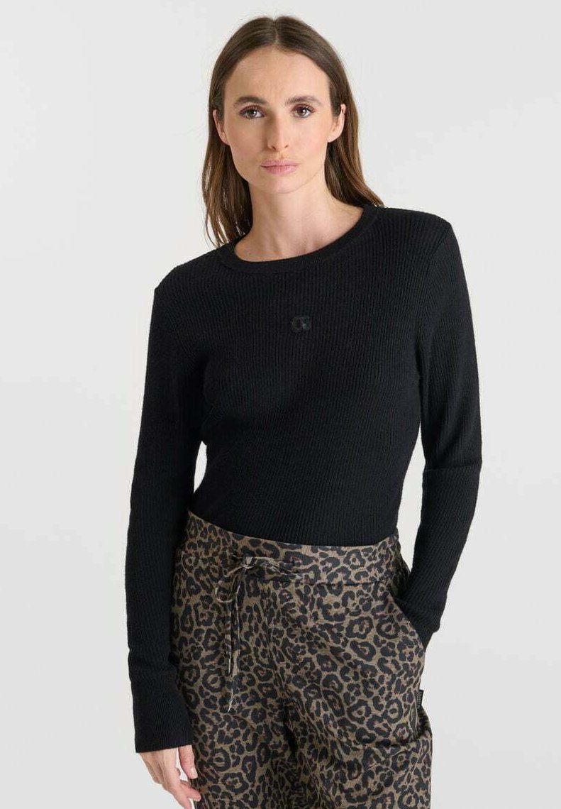 Pull noir à côtes avec des manches longues, un col rond et des poignets ajustés, associé à un pantalon à imprimé léopard avec une taille à cordon de serrage.