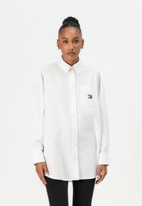 Hvit bomullsskjorte med knapper, spiss krage, oversized passform og en brystlomme med et lite flerfarget logo.