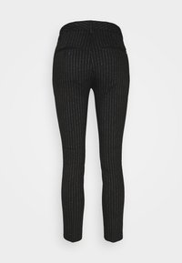 Pantalon noir ajusté avec de fines rayures blanches verticales, deux poches arrière à boutons, vu de dos sur un fond uni.