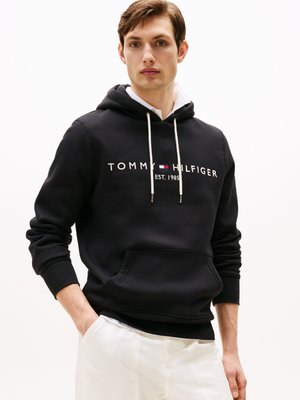 Black hoodie made of cotton blend, featuring a kangaroo pocket, white drawstrings, and red/blue logo with "TOMMY HILFIGER EST. 1985" text.