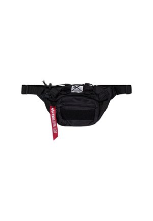 Sort taktisk bæltetaske med flere lynlåslommer, justerbar rem, elastisk snor og en rød mærkat med teksten "Remove Before Flight."