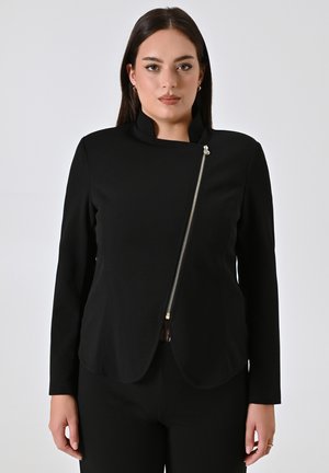 Schwarze Jacke mit langen Ärmeln, hochgearbeitetem Kragen und asymmetrischer Front. Verfügt über einen goldenen Reißverschluss an der Seite und eine glatte Stofftextur.