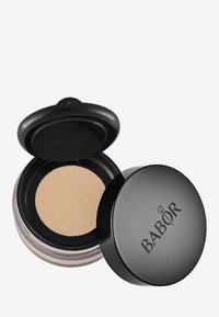 Fond de teint compact dans un contenant noir avec une base transparente, présentant une surface de poudre beige lisse et un couvercle noir texturé à double couche.