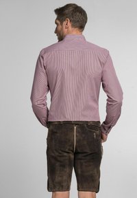 Gestreepte rood-witte blouse met lange mouwen en knoopmanchetten, gecombineerd met bruine suède shorts met een ritssluiting aan de achterkant en zijzakken.